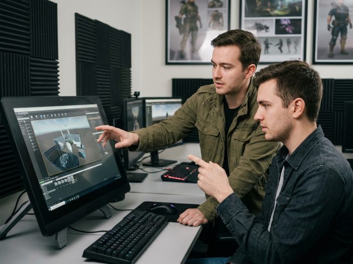 Deux étudiants d'une école de jeux vidéo analysant un moteur de jeu 3D dans un studio de développement professionnel